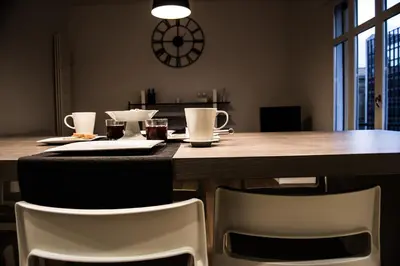 a dining room table with two white chairs and a clock at Home In City in Palermo