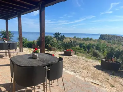 a table and chairs with a view of the ocean at Vista mare 360 in Scopello