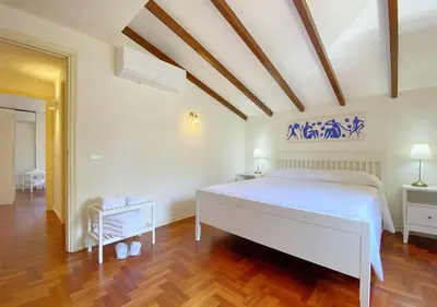 a bedroom with a white bed and a wooden floor at Solemar Sicilia - Villa Alma in Palermo