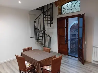 a dining room with a table and a spiral staircase at Vernagallo's house in Palermo