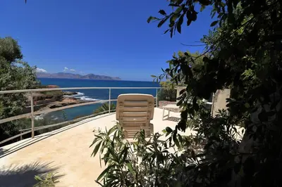a chair sitting on a patio next to the water at Villa Barbera - Terrace overlooking the sea in Bagheria