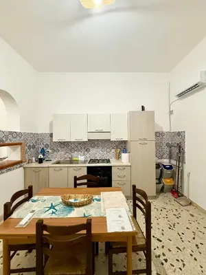a kitchen with a wooden table with chairs and a tableablish at Dimora Anastasia - Alloggio nel cuore di Balestrate in Balestrate