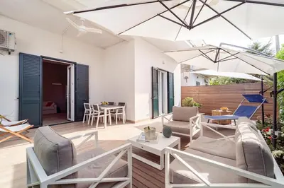 a patio with white furniture and an umbrella at Casa Clio - Mondello Home in Palermo