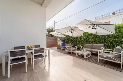 a patio with tables and chairs and umbrellas at Casa Clio - Mondello Home in Palermo