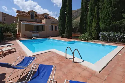 a swimming pool with chairs and a house at VFH Villa Cala del Cuore con piscina, 50 m dal mare in Santa Flavia