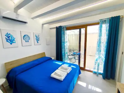 a bedroom with a blue bed and a window at Damasa House in Balestrate