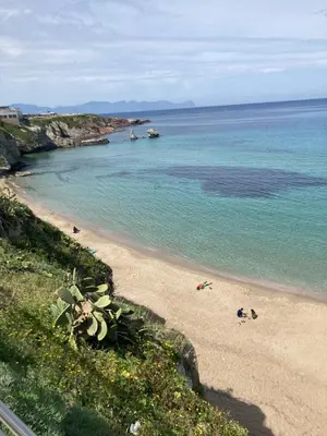 a beach with people on the sand and the water at La Casa dei Limoni - Your Sicilian Getaway near the sea in Terrasini in Terrasini