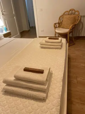 three towels are stacked on a bed with a chair at La Casa dei Limoni - Your Sicilian Getaway near the sea in Terrasini in Terrasini