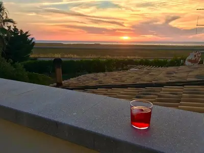 a glass of wine sitting on a ledge with the sunset at Casa Mulinazzo in Cinisi