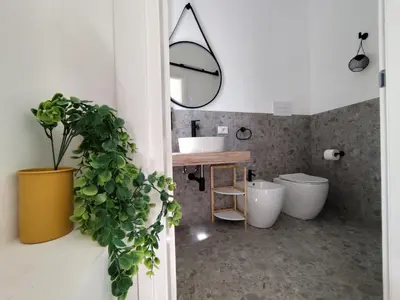 a bathroom with a sink and a mirror and a plant at Cà Mami Rooms in Palermo