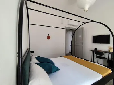 a bedroom with an iron canopy bed with blue pillows at Cà Mami Rooms in Palermo