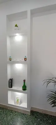 a wall with white shelves in a room with a plant at Airoldi Home in Palermo