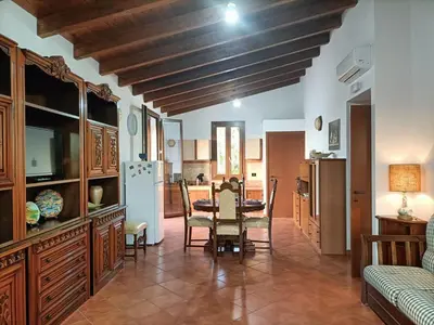 a dining room with a table and a kitchen at CAGNINA Apartments in Balestrate