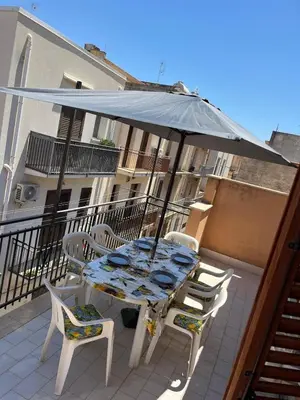 a table and chairs with an umbrella on a balcony at Casa Sole e Limone in Castellammare del Golfo