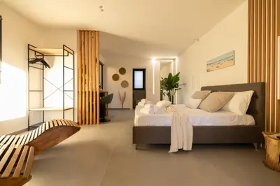 a bedroom with a large bed and a chair at Suite le palme in Aspra