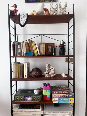 a book shelf with books and a clock on it at Corso Tugher in Palermo