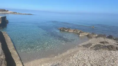 a beach with rocks and the ocean on a sunny day at Lucrezio Houses in Palermo
