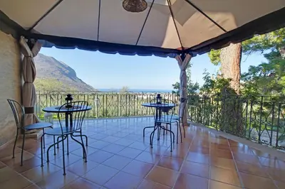 a patio with tables and chairs and a view of a mountain at Poggio di mare in Castelluzzo