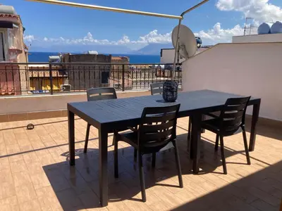 a black dining table and chairs on a balcony at Appartamento La Rosa dei Venti in Porticello
