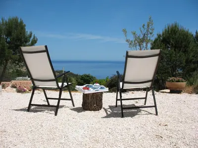two chairs sitting next to a tree stump with a table at Agave Scopello in Scopello