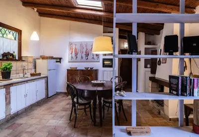 a kitchen and dining room with a table and chairs at Casa Ninfee, immersa nel verde con piscina in comune in Terrasini