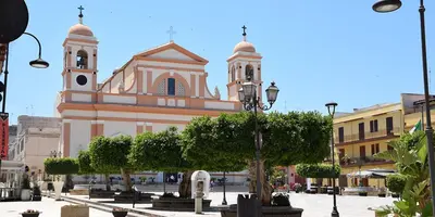 a large building with a clock tower on a street at West Sicily Beach in Balestrate