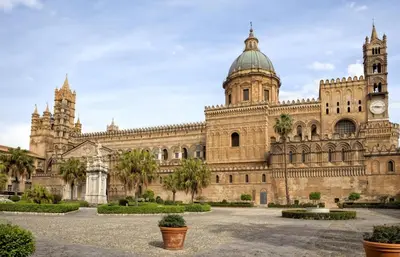 a large building with a clock tower and palm trees at La casettina di Dante in Palermo