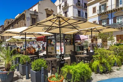 an outdoor cafe with tables and umbrellas at La casettina di Dante in Palermo