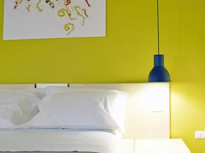a bedroom with a bed with a green wall and a blue lamp at Bio Hotel Palermo in Palermo