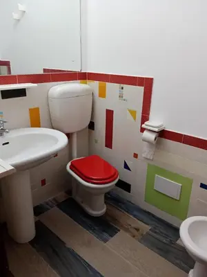 a bathroom with a red toilet and a sink at Casa Montalbano in Nuova Gibellina