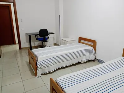 two beds in a room with a desk and a chair at Casa Montalbano in Nuova Gibellina