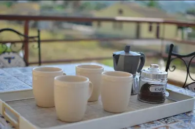 a tray with four cups and a tea kettle on a table at Maioliche Rooms in Campofelice di Roccella