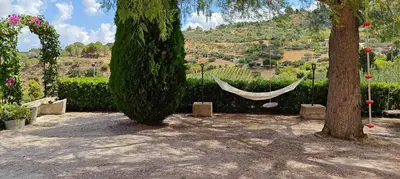 a hammock hanging between two trees in a garden at Villa Calatafimi Segesta in Calatafimi