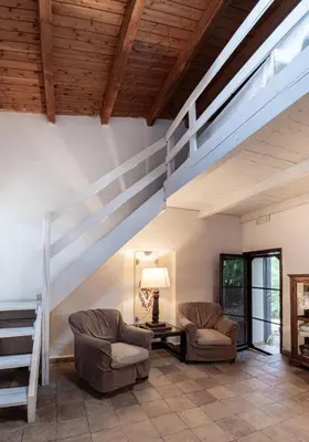 a living room with two chairs and a staircase at Casa Laghetto in the countryside with a shared pool in Terrasini