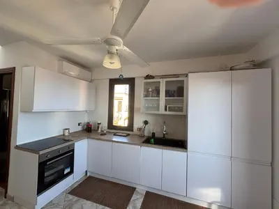 a kitchen with white cabinets and a ceiling fan at Sumarè in Isola delle Femmine