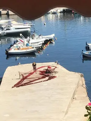 a man standing on a dock with boats in the water at Sumarè in Isola delle Femmine
