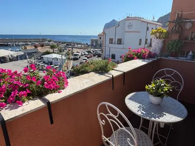 a balcony with tables and chairs and flowers at Sumarè in Isola delle Femmine