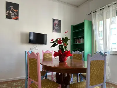 a dining room with a table with chairs and a television at Balhara Floridi House in Palermo