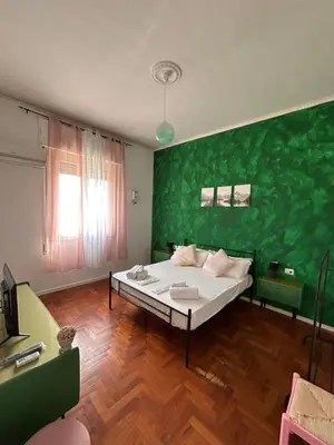 a bedroom with a large white bed with a green wall at Balhara Floridi House in Palermo