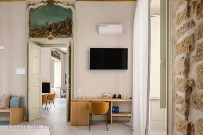 a living room with a table and a tv on a wall at Palazzo Cavarretta - Le Stanze dei Baroni in Palermo