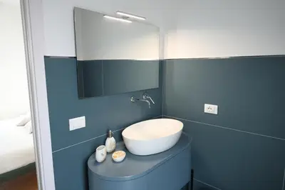 a blue bathroom with a sink and a mirror at Magnolia Home in Terrasini