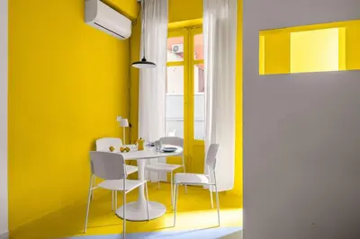 a yellow dining room with a white table and chairs at Sunny Apartament in Palermo