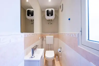 a bathroom with a toilet and a sink and two monitors on the wall at Ramona House in Palermo