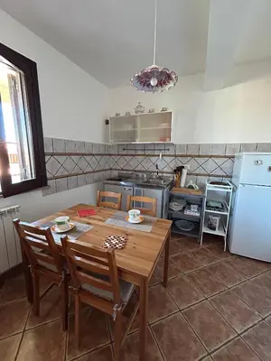 a kitchen with a wooden table and a table and chairs at Villa Irene in Isola delle Femmine