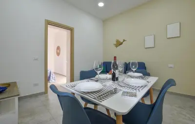 a dining room table with wine glasses and blue chairs at Lovely Home In Isola Delle Femmine With Wifi in Isola delle Femmine