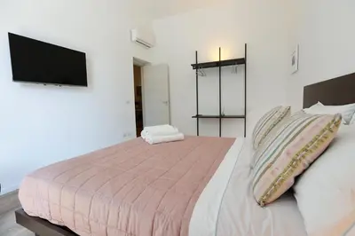 a bedroom with a bed with a tv on the wall at Devalù Politeama - Elegante appartamento al Politeama in Palermo