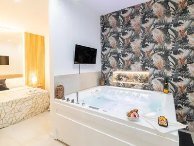 a large bath tub in a room with a bedroom at Cupido Apartment in Palermo