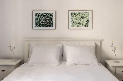a bedroom with a white bed with two pictures on the wall at La Casa del Genio in Palermo