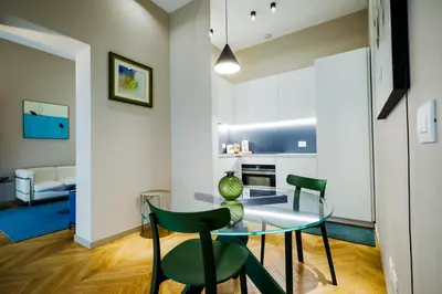 a dining room with a glass table and two green chairs at Exclusuite Design Apartment in Palermo