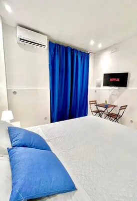 a bedroom with a bed with blue pillows and a television at Moonlight Rooms in Termini Imerese